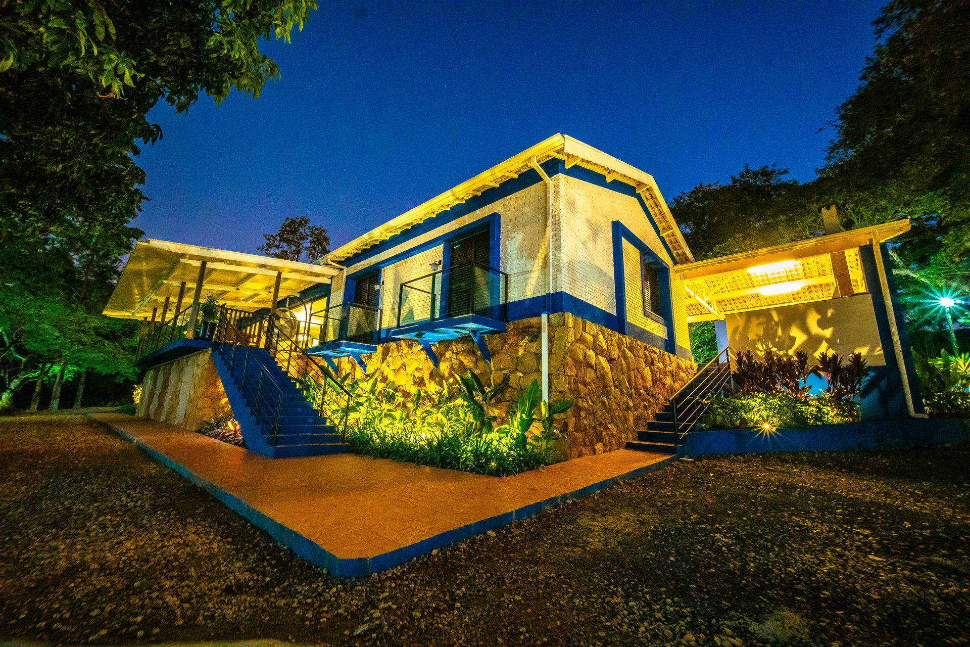 A casa da Quinta D’Aurora iluminada ao anoitecer, cercada por jardim